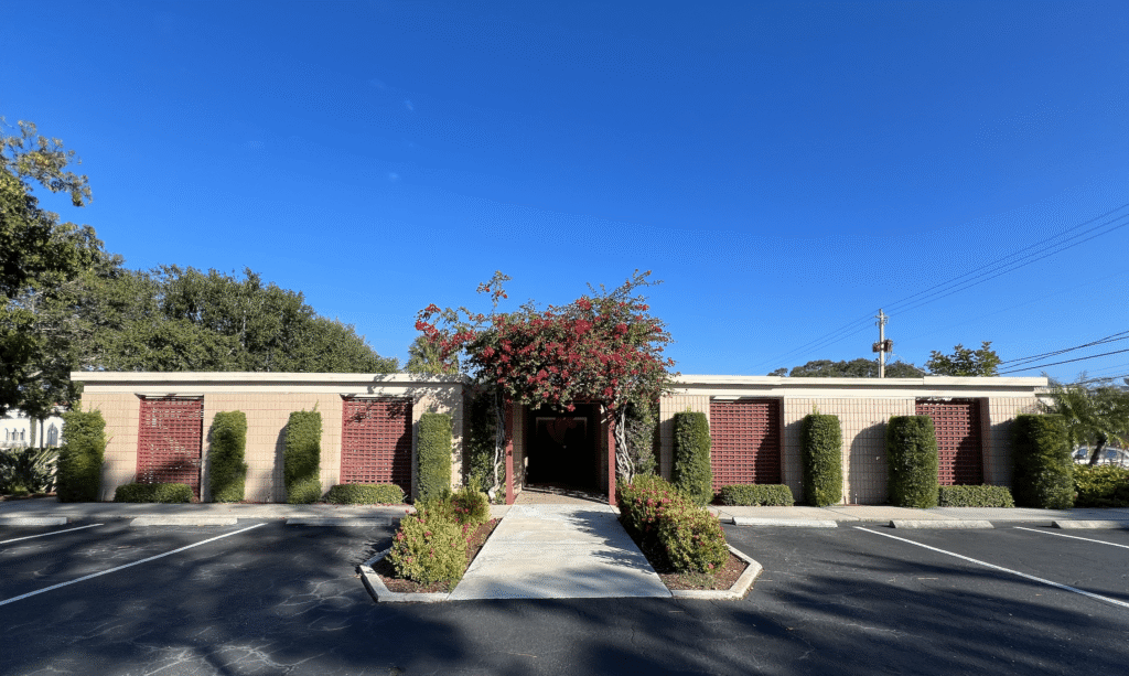 A Large Brick Building With A Clock On The Side Of A Road